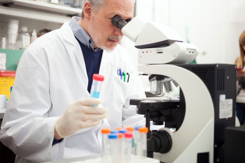 man using microscope in lab, higher education report on science and engineering